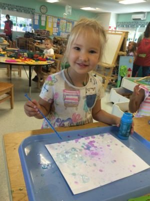 Girl painting with watercolors at a classroom table