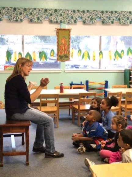 Teacher reading with children sitting on the classroom rug