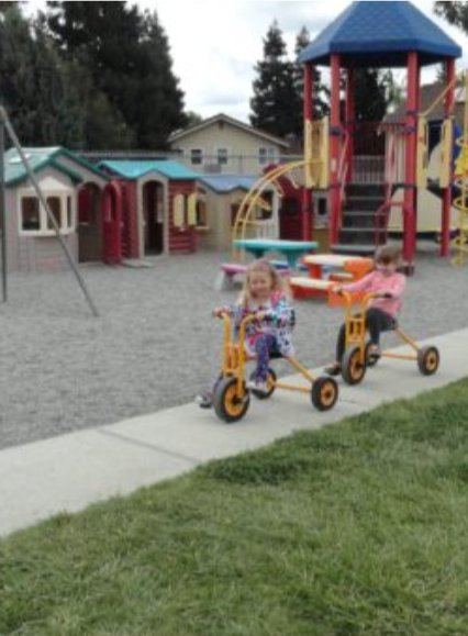 Two children riding tricycles on the playground